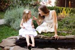 Mother With Daughter Near Pond Enjoying In Nature