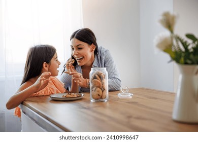 Mother and daughter in new kitchen, eating cookies.Happy loving family, mom and daughter enjoying together. - Powered by Shutterstock