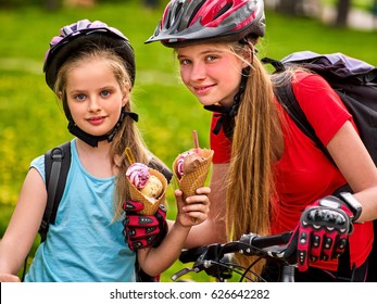 Mother And Daughter On Bicycle. Happy Family Eating Ice Cream And Ride Bike . Bikes Cycling Family. Kid Practice To Riding In Summer Park.