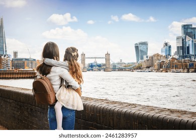 A mother and daughter on a city vacation looking at the skyline of London, England, with river Thames and Tower Bridge - Powered by Shutterstock