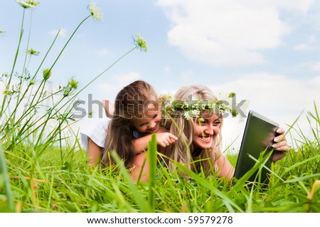mother and daughter on the maedow with notebook