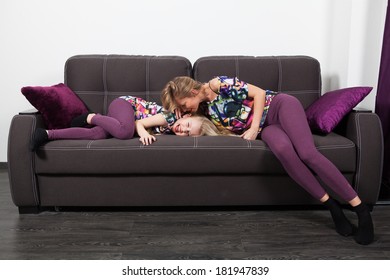 Mother and daughter on sofa lying on sofa in identical clothes