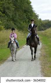 Mother and daughter on a trail ride with pony and horse.