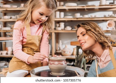 mother and daughter painting ceramic pot in pottery workshop - Powered by Shutterstock