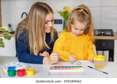 Mother And Daughter Painting At Home. Cute Little Kid In Yellow Sweater Having Fun With Parent And Paints. Concept Of Early Childhood Education, Hobby, Talent, Preschool Leisure And Parenting