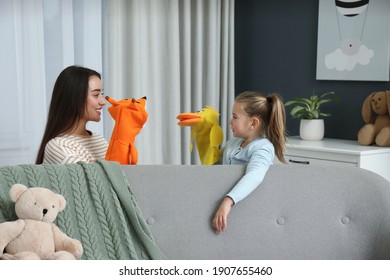 Mother And Daughter Performing Puppet Show At Home