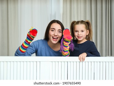 Mother And Daughter Performing Puppet Show At Home