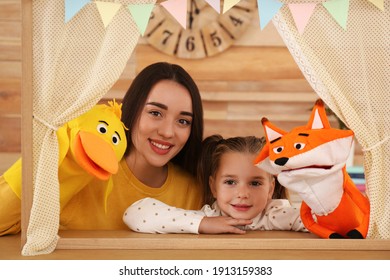 Mother And Daughter Performing Puppet Show At Home