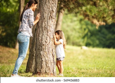 Mother and daughter play hide and seek at the park.