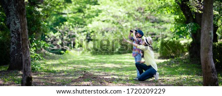 Mother and daughter playing with binoculars in the woods