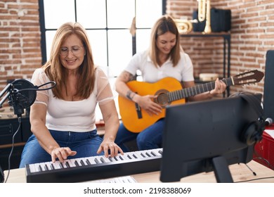 Mother and daughter playing classical guitar make selfie by the smartphone at music studio - Powered by Shutterstock