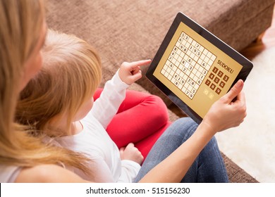 Mother and daughter playing game on tablet computer