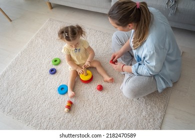 Mother And Daughter Are Playing Games In The Excitement Of The House. High Angle View Of The Cute Woman And Kid Girl Playing Educational Wooden Eco Friendly Toys At Home 