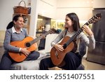 Mother and daughter playing guitar at home. A mother teaches her daughter to play the guitar.