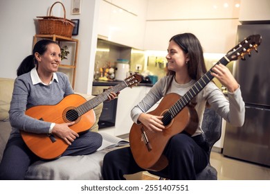 Mother and daughter playing guitar at home. A mother teaches her daughter to play the guitar. - Powered by Shutterstock