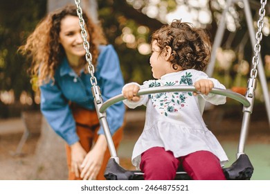 Mother and daughter playing on swing - enjoying a joyful family moment - smiling and having fun - outdoor activity, happiness and bonding in a natural setting. - Powered by Shutterstock