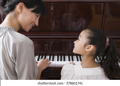 Mother and daughter playing the piano - Powered by Shutterstock