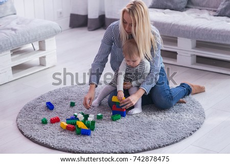 Mother and daughter playing together with colorful construction toys