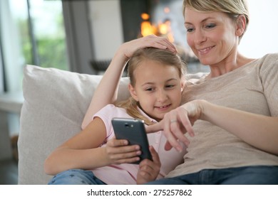 Mother and daughter playing together with smartphone - Powered by Shutterstock
