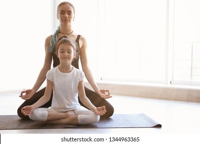 Mother and daughter practicing zen yoga in gym, space for text  - Powered by Shutterstock