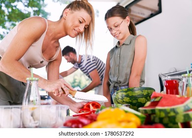 Mother and daughter preparing food for picnic