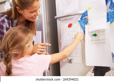 Mother And Daughter Putting Star On Reward Chart