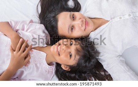 Mother and daughter relaxing on bed