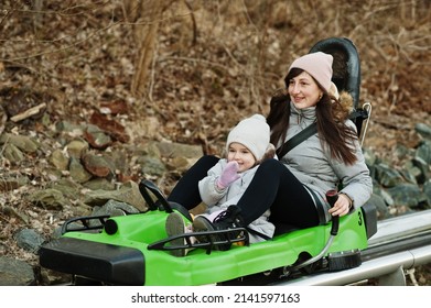 Mother With Daughter Ride Electric Sleigh On Rails. 