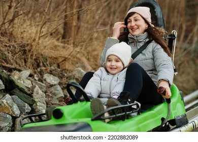 Mother With Daughter Ride Electric Sleigh On Rails. 