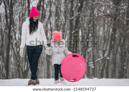 Mother with daughter riding on plate in winter park