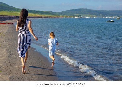 Mother And Daughter Running Behind The Sea