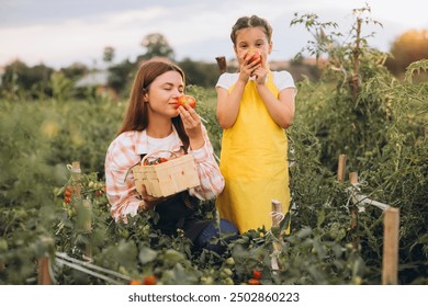 A mother and daughter savor the aroma of freshly picked tomatoes in a lush garden. The scene captures family bonding and appreciation of nature's bounty. - Powered by Shutterstock