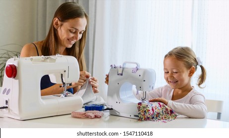 Mother and daughter is sewing on a machine. A woman using a needle. A mother and a daughter are spending time at home together, day time.