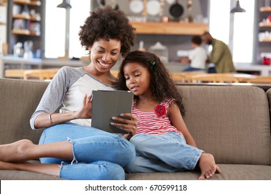 Mother And Daughter Sit On Sofa In Lounge Using Digital Tablet - Powered by Shutterstock