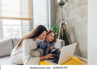 Mother And Daughter Siting On The Couch And Using Laptop