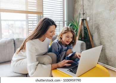 Mother and daughter siting on the couch and using laptop - Powered by Shutterstock