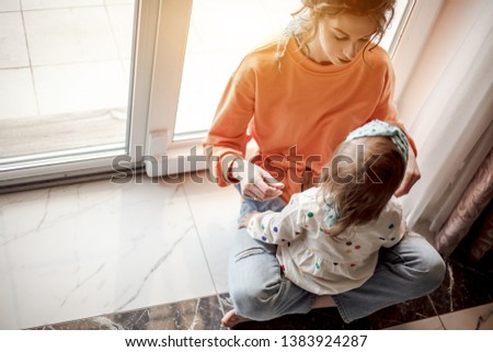 mother and daughter siting on the floor near the window. good morning.