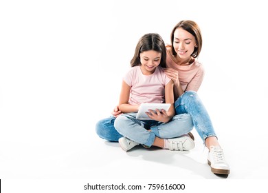 Mother And Daughter Sitting And Looking At Tablet On White