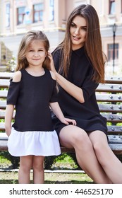 Mother And Daughter Sitting On The Bench Summer Warm Weather Yard In Town Girl And Woman Laughing Smile Speak Wearing The Same Dress A Family Day To Spend Time Together Happy Kid Child Baby Parent 