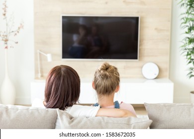 Mother And Daughter Sitting On Sofa And Watching Tv, Single Mother Concept, Back View