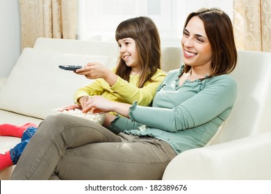 Mother And Daughter Sitting On Sofa At Their Home,eating Popcorn And Watching Tv,Family Time