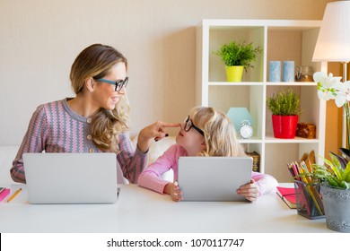 Mother and daughter sitting at table and using computers together - Shutterstock ID 1070117747