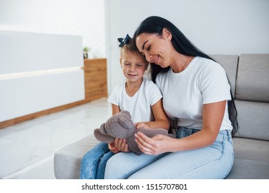 Mother And Daughter Sitting Together On The Sofa In Waiting Room Of Clinic.