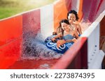 Mother and daughter sliding down water slide, sitting together at inflatable ring and making water splashes. Family vacation in aquapark.