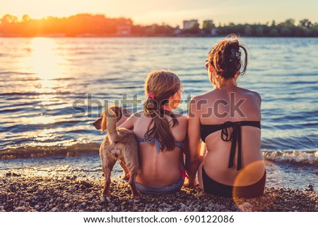 Mother, daughter and small yellow dog enjoying on the beach