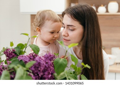 Mother With Daughter Smelling Flowers At Home. Happy Family Moments