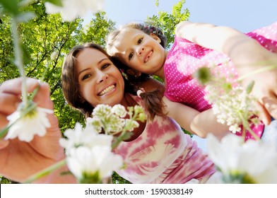 Mother And Daughter Smelling Flowers, Low Angle View