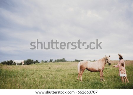 Mother and daughter stand on the field before a horse