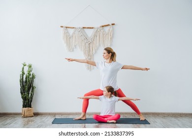 Mother And Daughter Stand Together In Second Warrior Pose. Yoga Paired With A Child. Relaxation And Harmony With Yourself And Your Body. Virabhadrasana.High Quality Photo