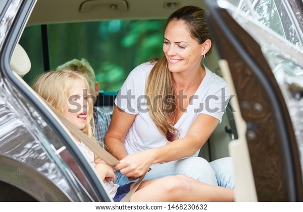 Mother\
and daughter strapping on a seat belt in the\
car